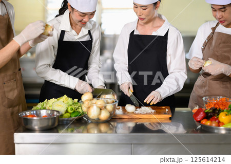 Chef instructor guiding students in hands on kitchen training Chef instructor guiding students in hands on kitchen training 125614214