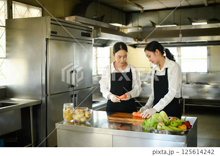 Female culinary student preparing fresh vegetables during a cooking class 125614242