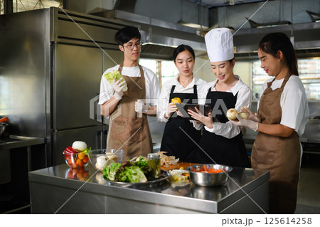 Cooking school instructor guiding a group of culinary students during a lesson Cooking school instructor guiding a group of culinary students during a lesson 125614258