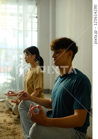 Young couple practicing yoga and meditation together at home 125614290