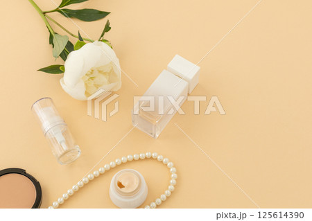 Women cosmetics set with costume jewelry and a peony flower. 125614390