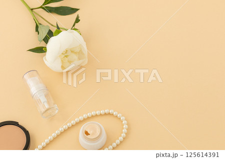 Women cosmetics set with costume jewelry and a peony flower. Women cosmetics set with costume jewelry and a peony flower. 125614391