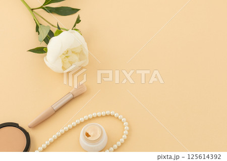 Women cosmetics set with costume jewelry and a peony flower. 125614392