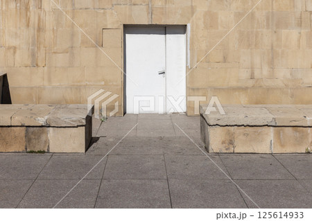 A simple white door set into a textured stone wall, background photo 125614933