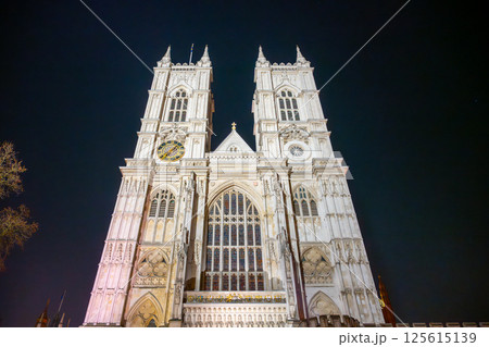 Westminster Abbey stands majestically at night in London, showcasing its stunning Gothic architecture. The towers are lit beautifully against the dark sky, creating a captivating sight. 125615139