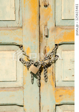 Chain with a padlock on a wooden door. Chain with a padlock on a wooden door. 125615461