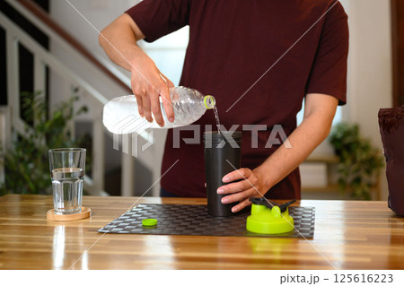 Young caucasian man preparing a protein shake in a cozy home kitchen Young caucasian man preparing a protein shake in a cozy home kitchen 125616223
