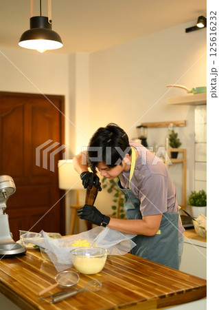 Young man seasoning freshly made butter with ground pepper in a home kitchen Young man seasoning freshly made butter with ground pepper in a home kitchen 125616232