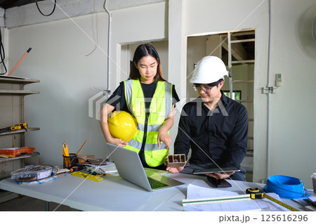 Male and female engineers reviewing construction plans in a renovation workspace Male and female engineers reviewing construction plans in a renovation workspace 125616296