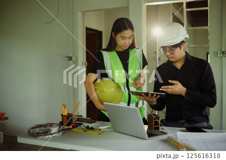 Male and female engineers reviewing construction plans in a renovation workspace Male and female engineers reviewing construction plans in a renovation workspace 125616318