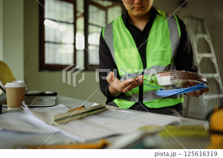 Close up of technician examining cable spools during building renovation Close up of technician examining cable spools during building renovation 125616319