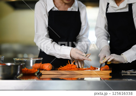 Young chefs slicing carrots during a hands on cooking class Young chefs slicing carrots during a hands on cooking class 125616338