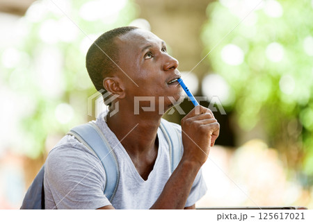 young student, a man studying sitting in town after school young student, a man studying sitting in town after school 125617021