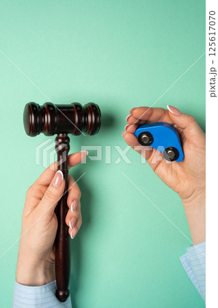 Judge's hammer and toy blue car in hands. Traffic and driving rules concept. Auto accident, drunk driving, court of law, justice 125617070