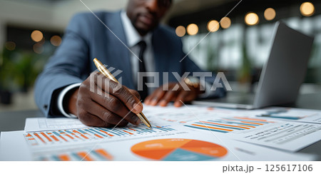 Businessman analyzing financial charts, graphs, and documents office desk, focused 125617106