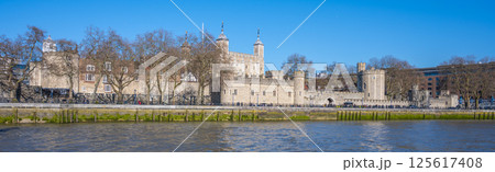 Visitors admire the historic Tower of London from Tower Wharf, enjoying the clear blue sky and the reflections on the River Thames. The tower stands as a symbol of history and strength. Visitors admire the historic Tower of London from Tower Wharf, enjoying the clear blue sky and the reflections on the River Thames. The tower stands as a symbol of history and strength. 125617408