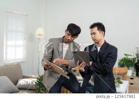 Business Collaboration and Insight Sharing. Two professionals reviewing data and discussing strategies in an office. 125617981