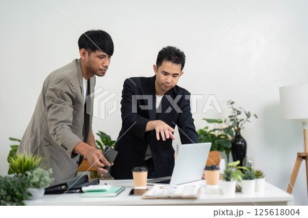 Engaging Presentation and Team Interaction. Professionals collaborating on a laptop in a modern office. 125618004