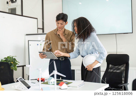 Collaboration and Sustainability. Two professionals discussing sustainable solutions in an office environment. Collaboration and Sustainability. Two professionals discussing sustainable solutions in an office environment. 125618006