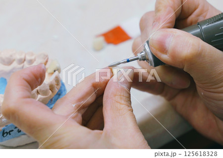 Masterful crafting of dentures by skilled dental technician in workshop 125618328