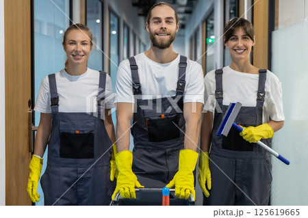 Cleaning team walking in the office corridor with cleaning equipment 125619665