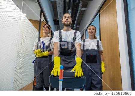 Cleaning team walking in the office corridor with cleaning equipment Cleaning team walking in the office corridor with cleaning equipment 125619666