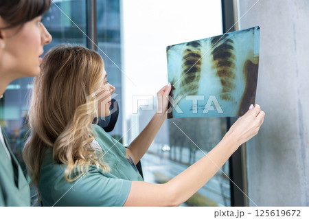 Doctors in radiology office discussing health diagnosis looking at x-ray image Doctors in radiology office discussing health diagnosis looking at x-ray image 125619672