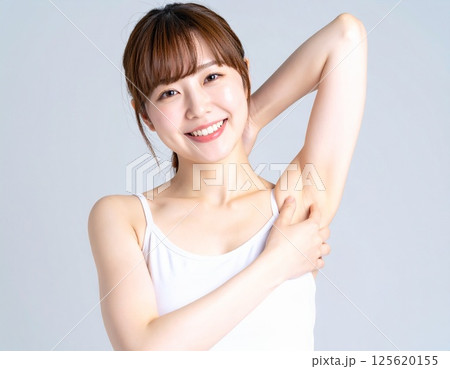 腕を上げるタンクトップ姿の女性と脇脱毛イメージ 125620155
