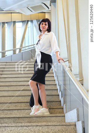 A woman stands on the steps of a staircase in a passageway 125620440