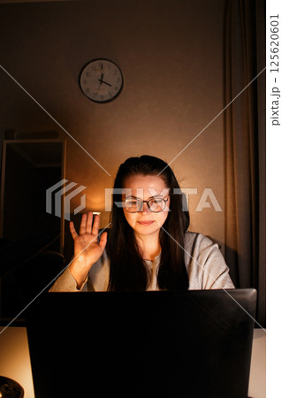 Young millennial woman starting video conference with greeting gesture. Smiling and friendly employee participating in remote video call. 125620601