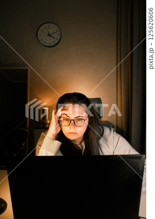 Young freelance accountant working remotely on laptop at home. Managing finances of business. Calculating incomes and expenses. Focusing on process. 125620606