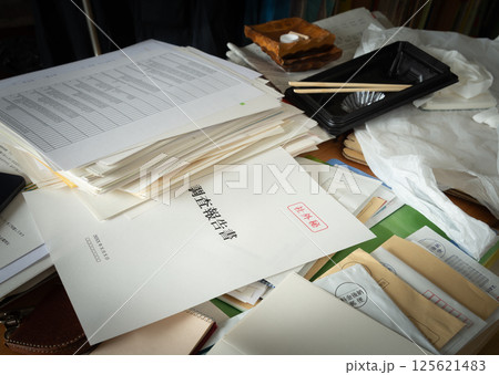 書類に紛れ込んでいた調査報告書　雑然とした机に調査報告書　社外秘　内部資料 125621483