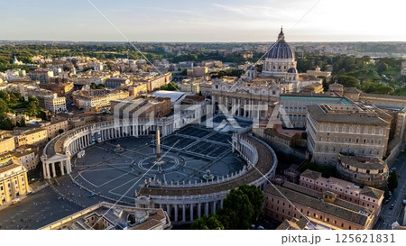 Stunning aerial view of St. Peter's Basilica and St. Peter's Square in Vatican City at sunset, surrounded by historic architecture and lush greenery 125621831