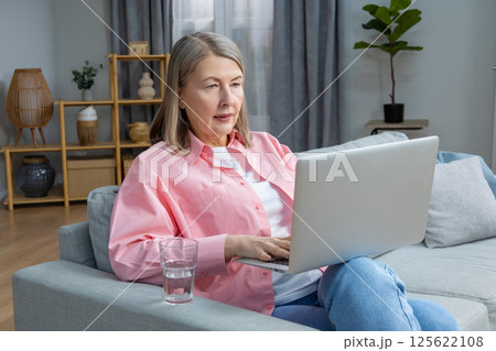 Mid aged woman in pink shirt feeling unwell and having a headache 125622108