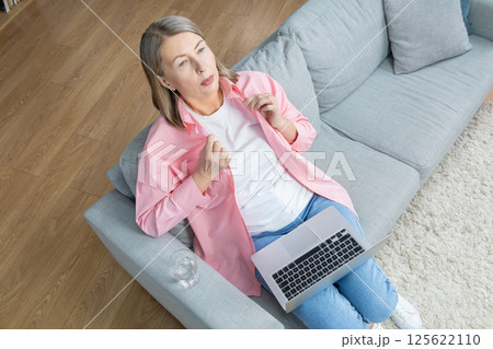 Mid aged woman in pink shirt feeling unwell and having a headache Mid aged woman in pink shirt feeling unwell and having a headache 125622110