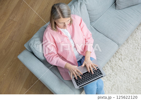 Top view of a woman sitting on the sofa with a laptop 125622120