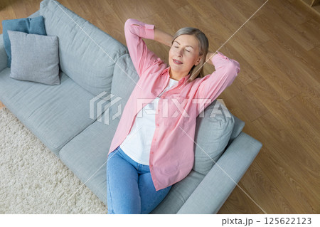Woman in pink shirt sitting on the sofa with a relaxed look Woman in pink shirt sitting on the sofa with a relaxed look 125622123