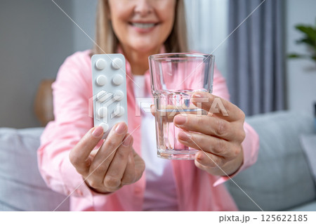 Mid aged woman in pink shirt taking HRT pills Mid aged woman in pink shirt taking HRT pills 125622185