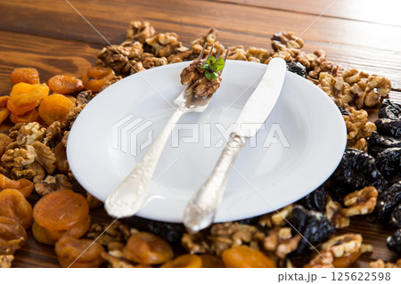 Clean empty plate and Nuts, dried apricots and prunes on a wooden table 125622598
