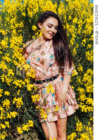 woman in summer dress inhales the aroma of spring flowers 125622646