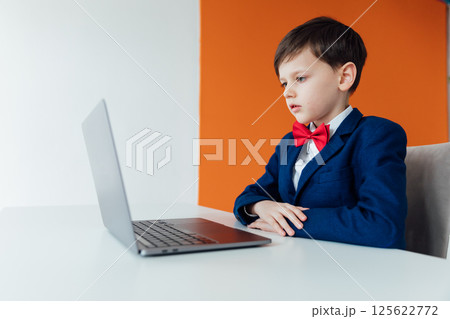Boy in school uniform working on laptop Boy in school uniform working on laptop 125622772