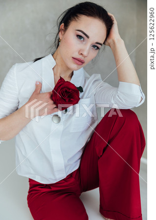 Beautiful brunette woman with red rose near her face Beautiful brunette woman with red rose near her face 125622960
