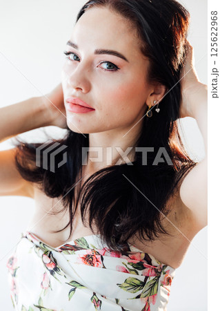 Portrait of a beautiful brunette woman in a dress with flowers Portrait of a beautiful brunette woman in a dress with flowers 125622968