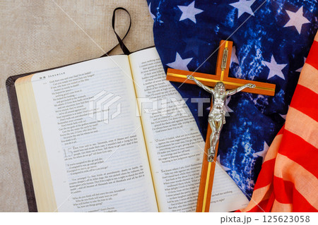 24 April 2025 Washington DC US Bible opened to page with crucifix folded flags placed nearby, blending faith patriotism in one view. 24 April 2025 Washington DC US Bible opened to page with crucifix folded flags placed nearby, blending faith patriotism in one view. 125623058