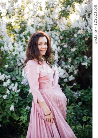 woman in summer dress with spring lilac flowers 125623059