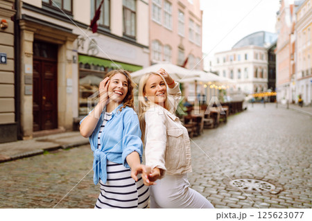 Two beautiful women are walking down the street. Fun and walking concept. Active lifestyle. Two beautiful women are walking down the street. Fun and walking concept. Active lifestyle. 125623077