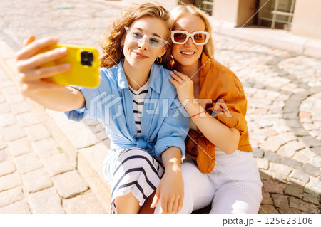 Happy female tourists take selfie using phone while walking along the streets of Europe. lifestyle. 125623106