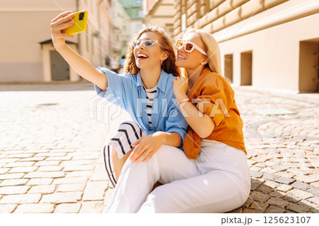Happy female tourists take selfie using phone while walking along the streets of Europe. lifestyle. Happy female tourists take selfie using phone while walking along the streets of Europe. lifestyle. 125623107