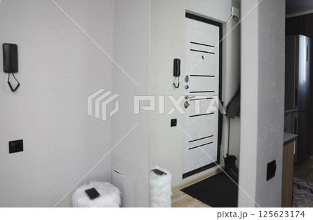 modern entryway interior with closed white front door, black hardware, home hallway decor with wall-mounted intercom, fluffy white stool, real estate, apartment rental, smart home tech modern entryway interior with closed white front door, black hardware, home hallway decor with wall-mounted intercom, fluffy white stool, real estate, apartment rental, smart home tech 125623174
