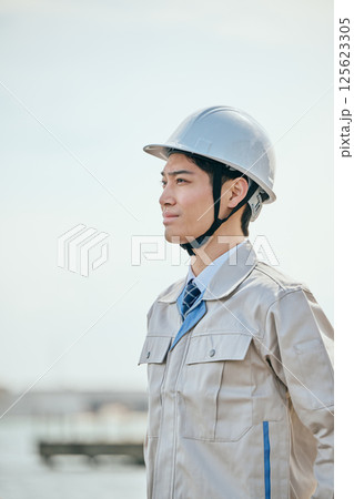 遠くを見つめる作業着姿の20代の若い男性 遠くを見つめる作業着姿の20代の若い男性 125623305